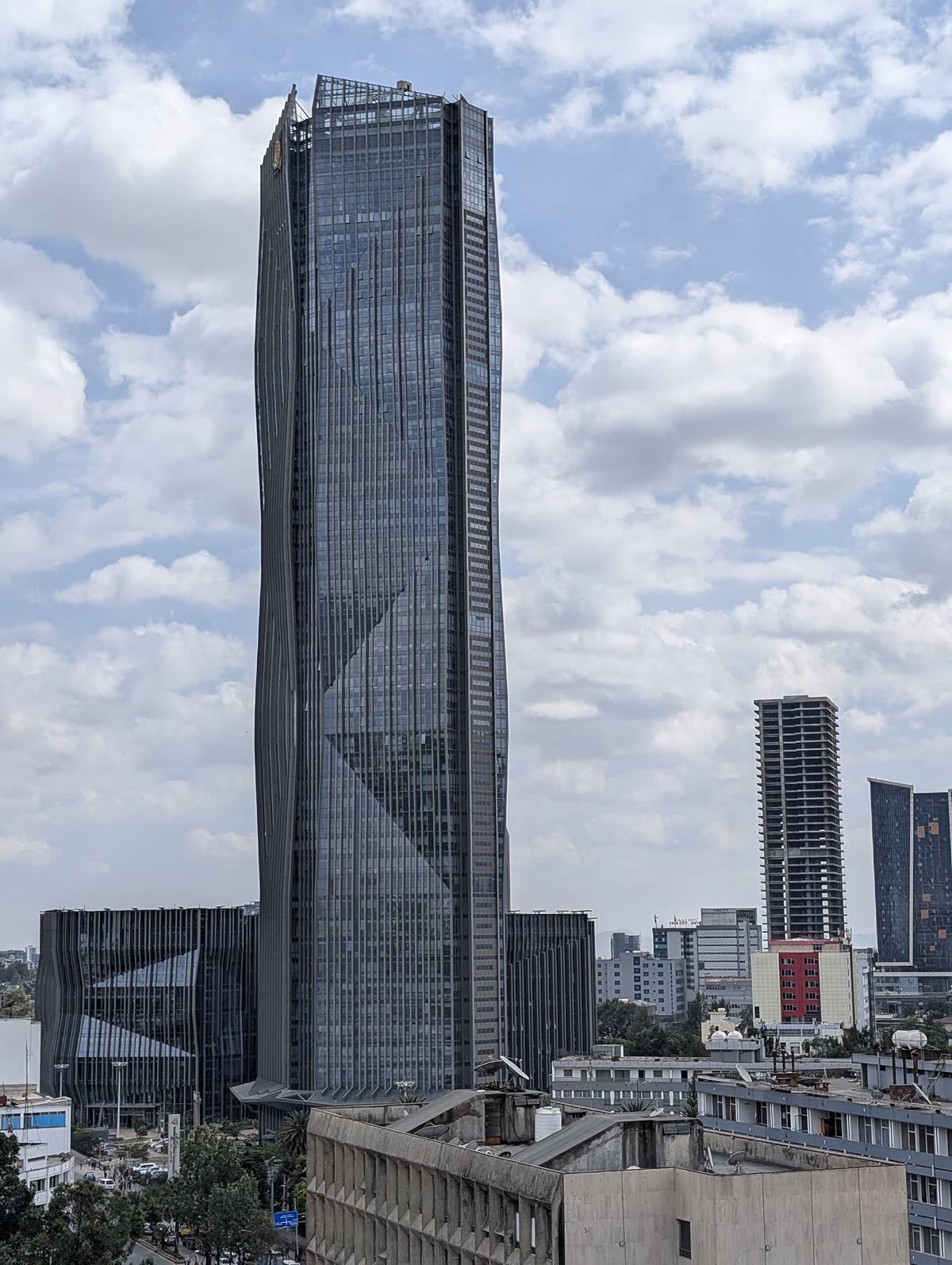 A glass office tower rising over Addis Ababa's business district under a bright cloudy sky