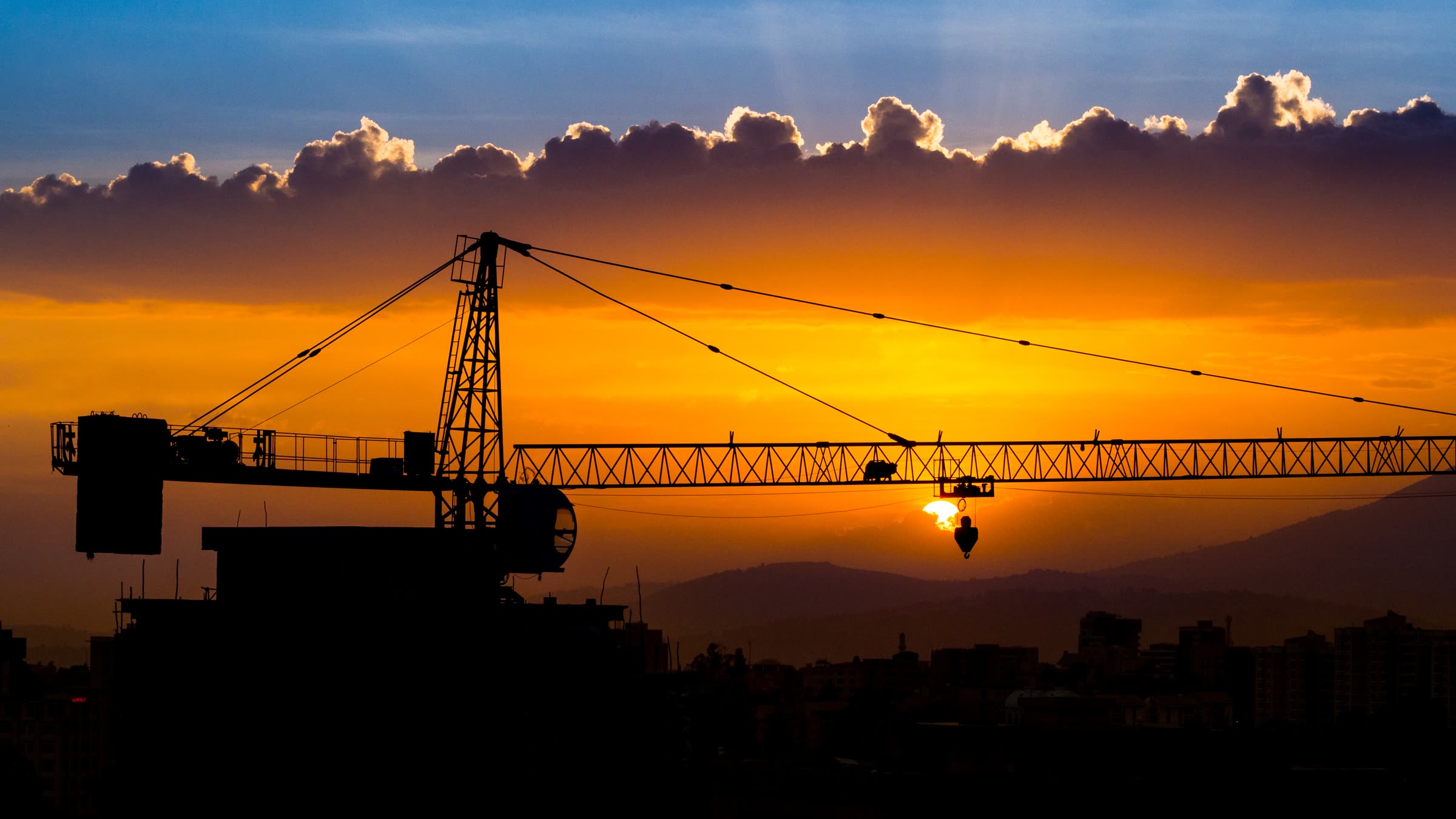 A tower crane silhouetted against the sunset over Addis Ababa